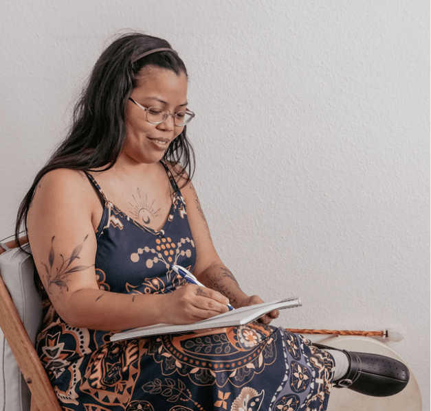 thérapeute holistique exerçant à Lausanne, Morges et Renens, dans le canton de Vaud en Suisse, assise dans son cabinet, elle prend des notes sur un carnet au sujet de ses séances de constellations familiales et systémiques et thérapie psycho-spirituelles