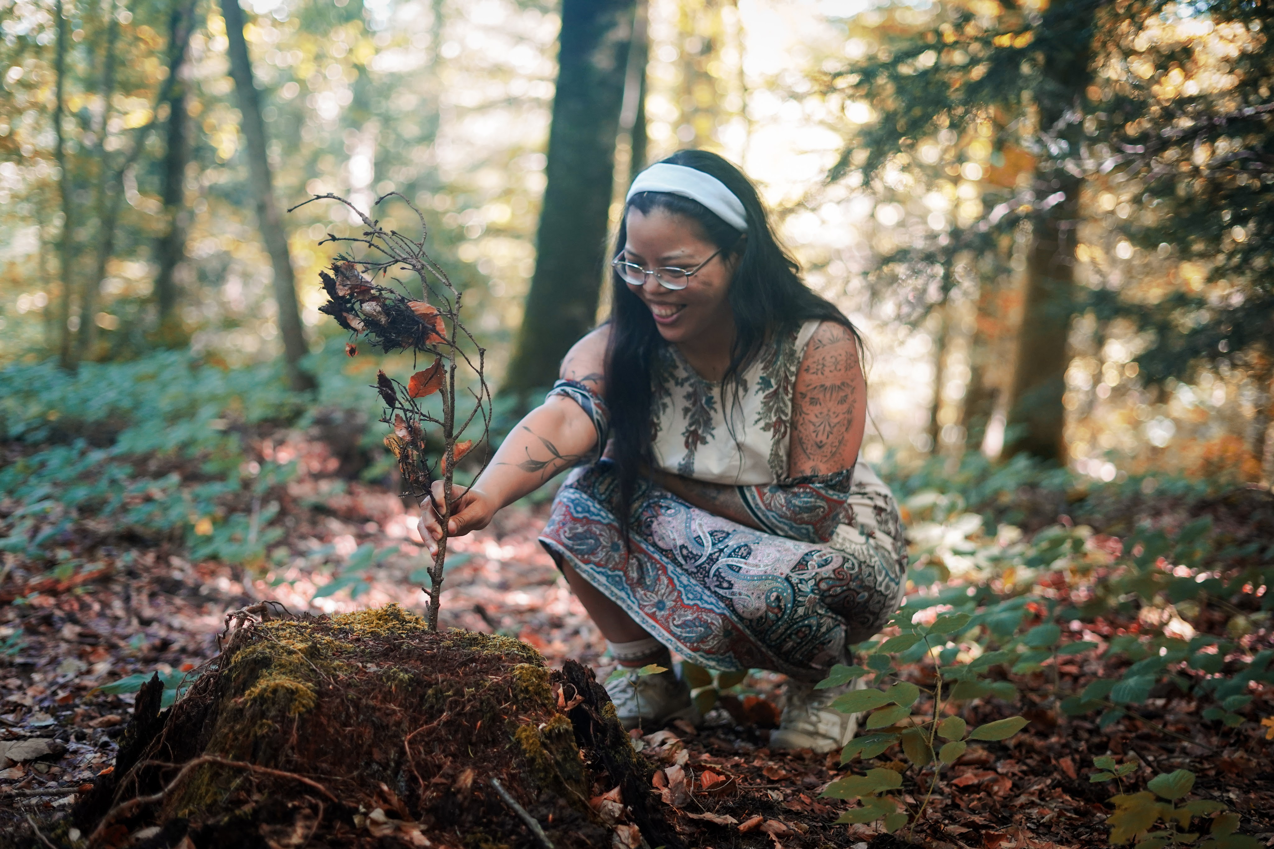 Image d'une thérapeute en constellation familiale et systémique, coach holistique et human design accroupie dans la forêt, lors d'une séance de constellations en groupe, dans le canton de Vaud, près de Lausanne, Renens et Morges.