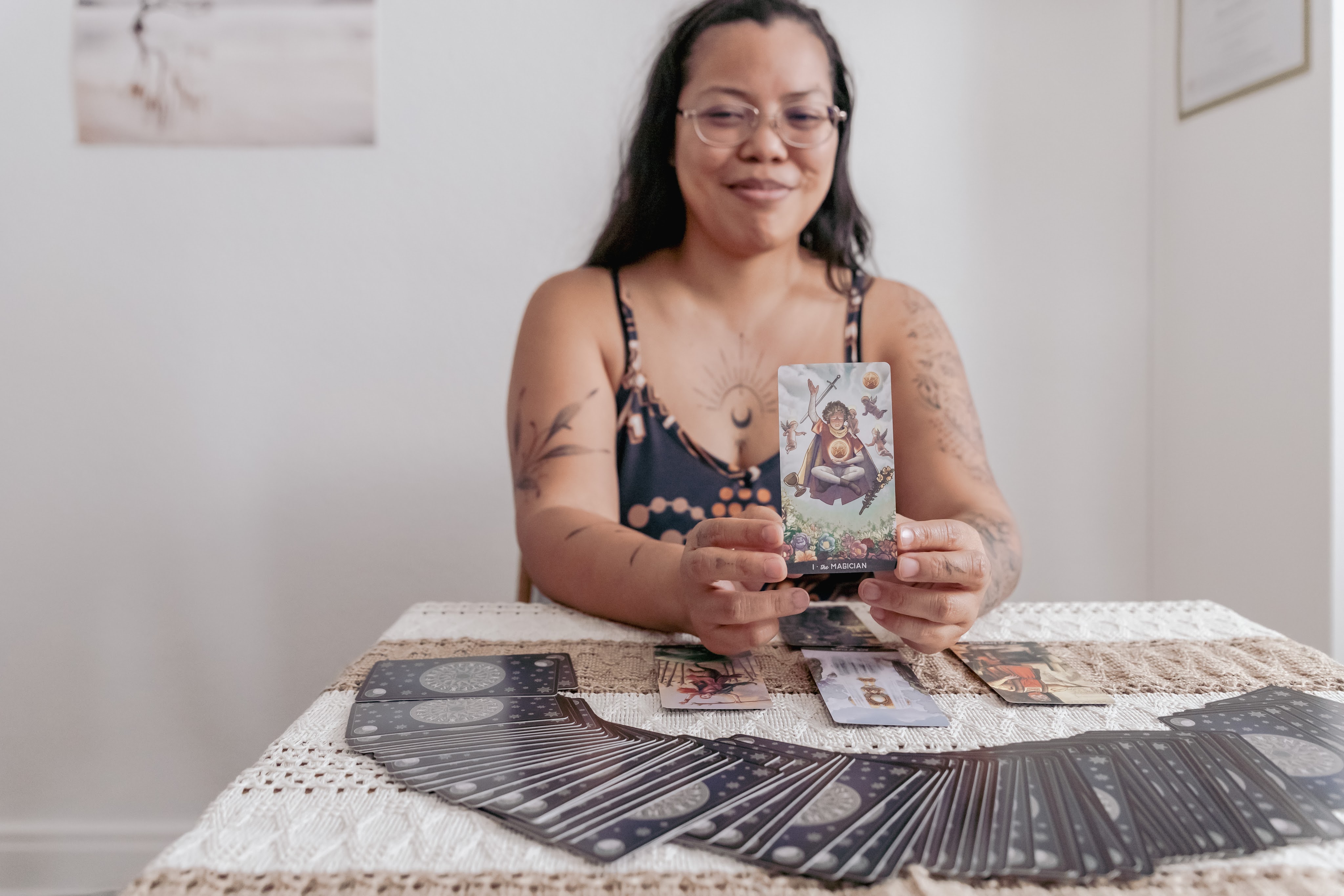 portrait d'une thérapeute en constellation familiale et systémique exerçant près de Lausanne, en Suisse, dans le canton de Vaud. Elle se tient assise à une table et tire des cartes de tarot dans une optique de guidance intuitive à travers la médiumnité et le human design. 