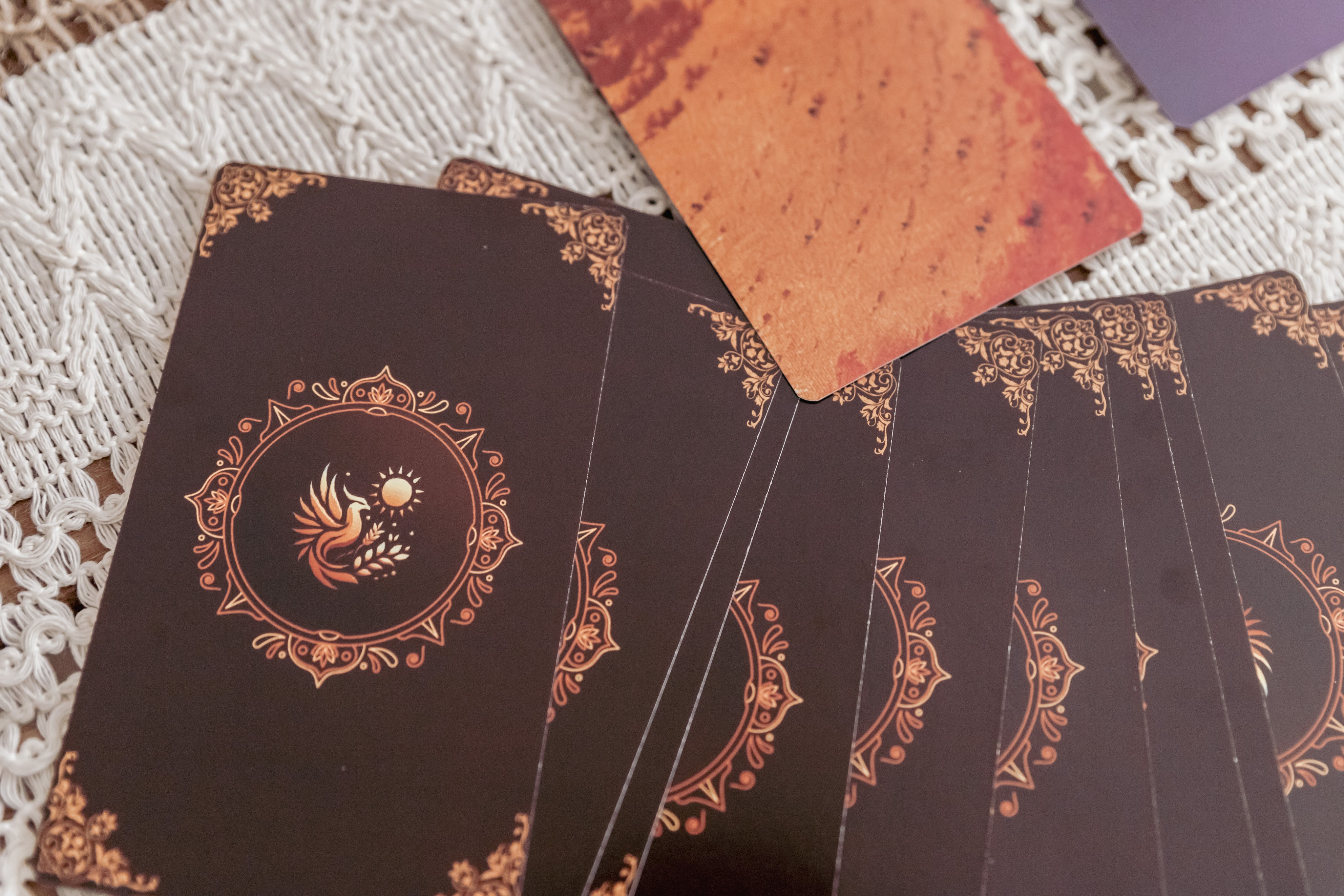 gros plan sur les cartes d'un oracle canalisé par une coach holistique et thérapeute en constellation familiale et systémique de groupe à Lausanne (Vaud, Suisse romande). Les cartes sont étalées sur la table et l'une d'elles est retournée.